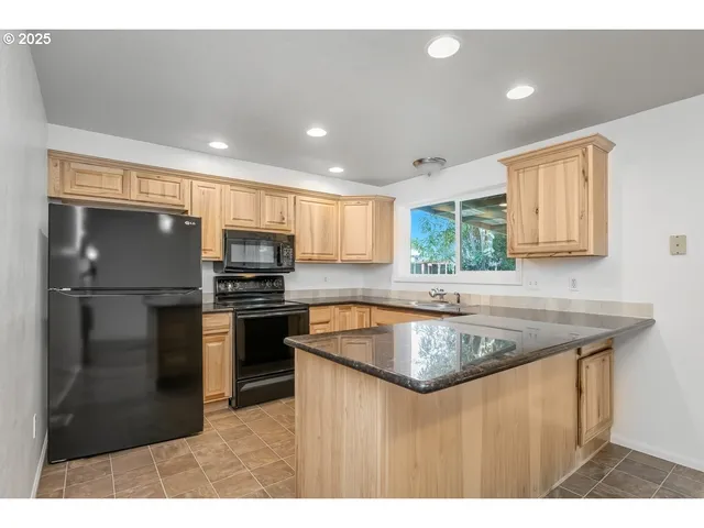 a kitchen with stainless steel appliances granite countertop a sink a stove a refrigerator a microwave a counter top and oven