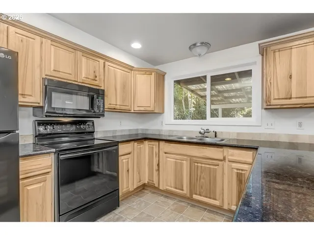 a kitchen with stainless steel appliances granite countertop a stove a sink and a microwave