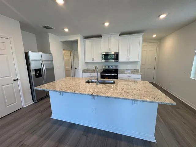 a kitchen with stainless steel appliances granite countertop a white refrigerator a stove a sink and dishwasher