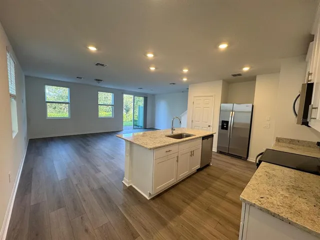 a large kitchen with a center island wooden floor and stainless steel appliances