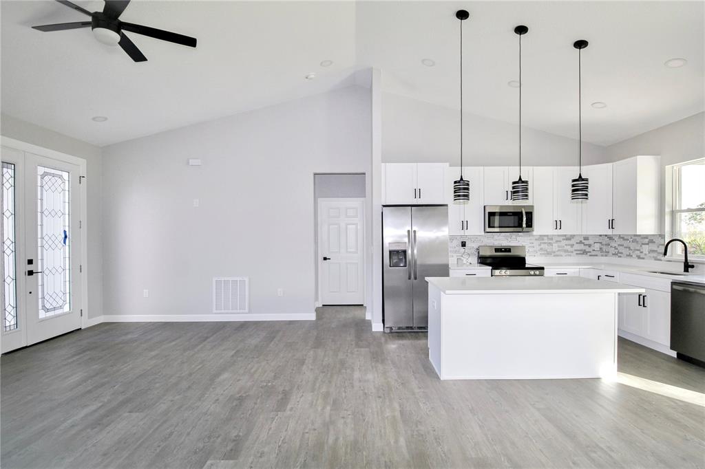 7335 Domenico Street Sebring, FL 33872 - Photo 12 of 38 a kitchen with stainless steel appliances a refrigerator a sink dishwasher a stove with white cabinets and wooden floor