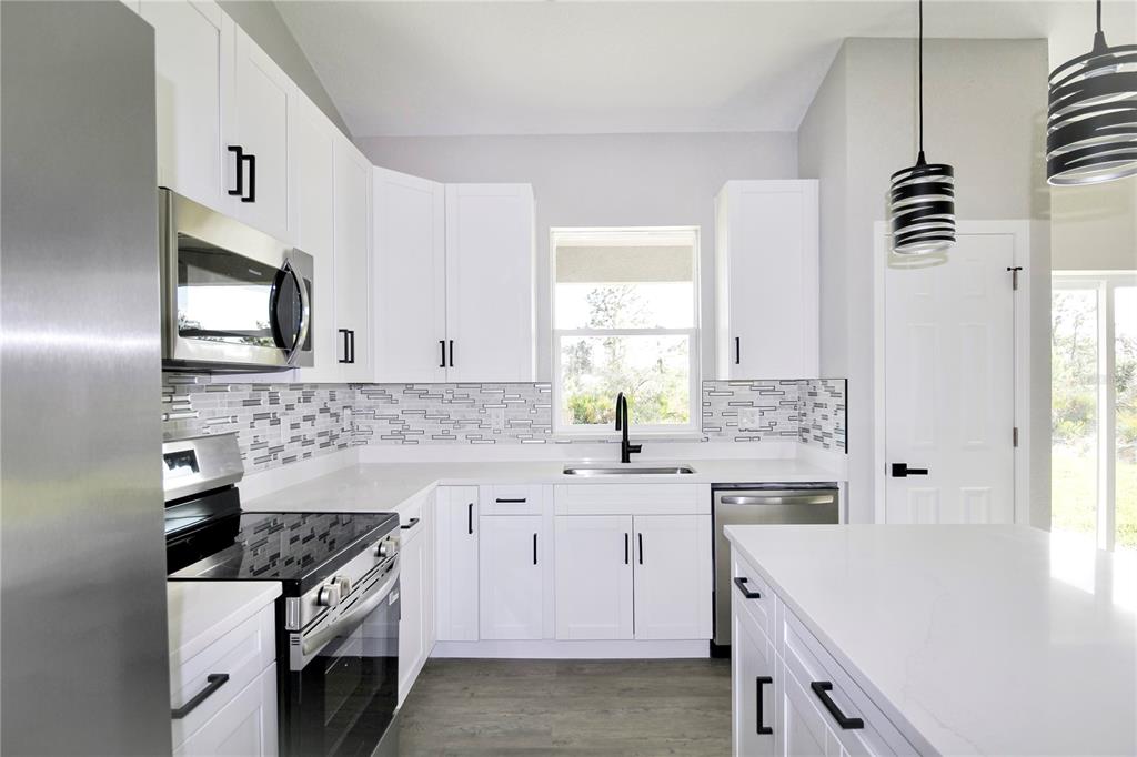 7335 Domenico Street Sebring, FL 33872 - Photo 13 of 38 a kitchen with a sink stove and cabinets