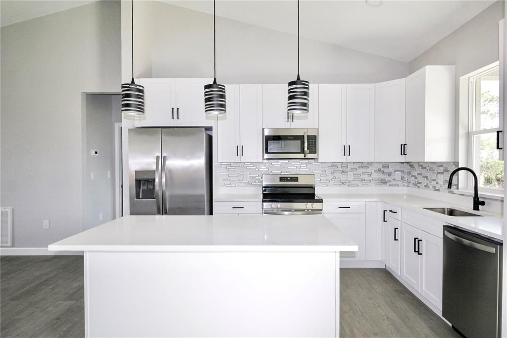 7335 Domenico Street Sebring, FL 33872 - Photo 14 of 38 a kitchen with stainless steel appliances a sink a stove a refrigerator a center island and cabinets