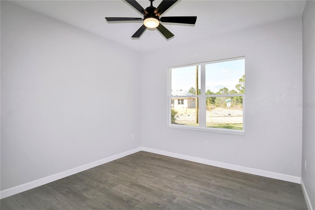 7335 Domenico Street Sebring, FL 33872 - Photo 25 of 38 an empty room with wooden floor fan and windows