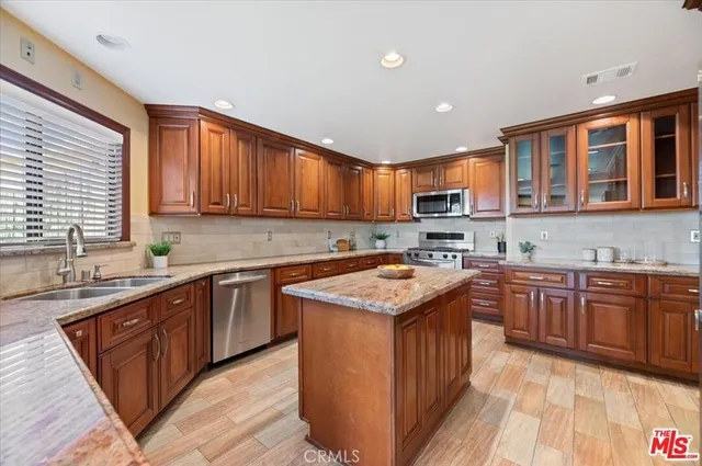 a kitchen with stainless steel appliances granite countertop wooden cabinets a sink and a stove