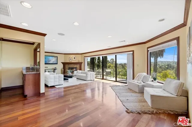 a living room with furniture large window and wooden floor