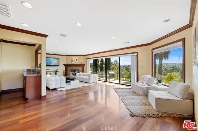 a living room with furniture large window and wooden floor