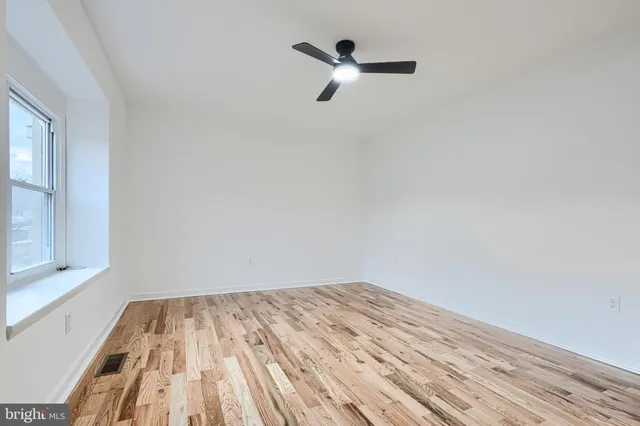 a view of a room with wooden floor and a ceiling fan