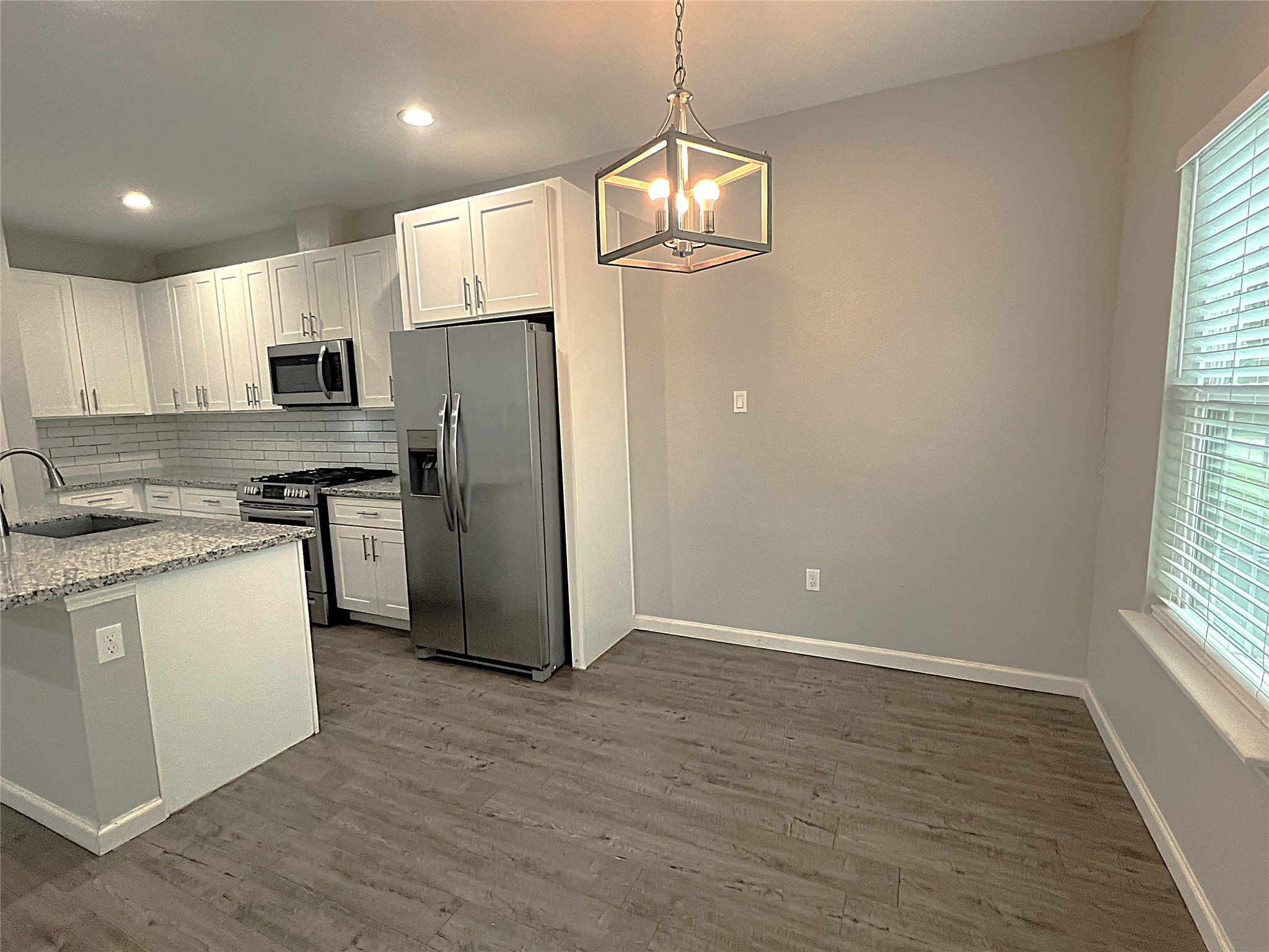 5779 Belarbor Street, Unit A Houston, TX 77033 - Photo 3 of 27 a kitchen with stainless steel appliances granite countertop a refrigerator a sink dishwasher a stove and white cabinets with wooden floor