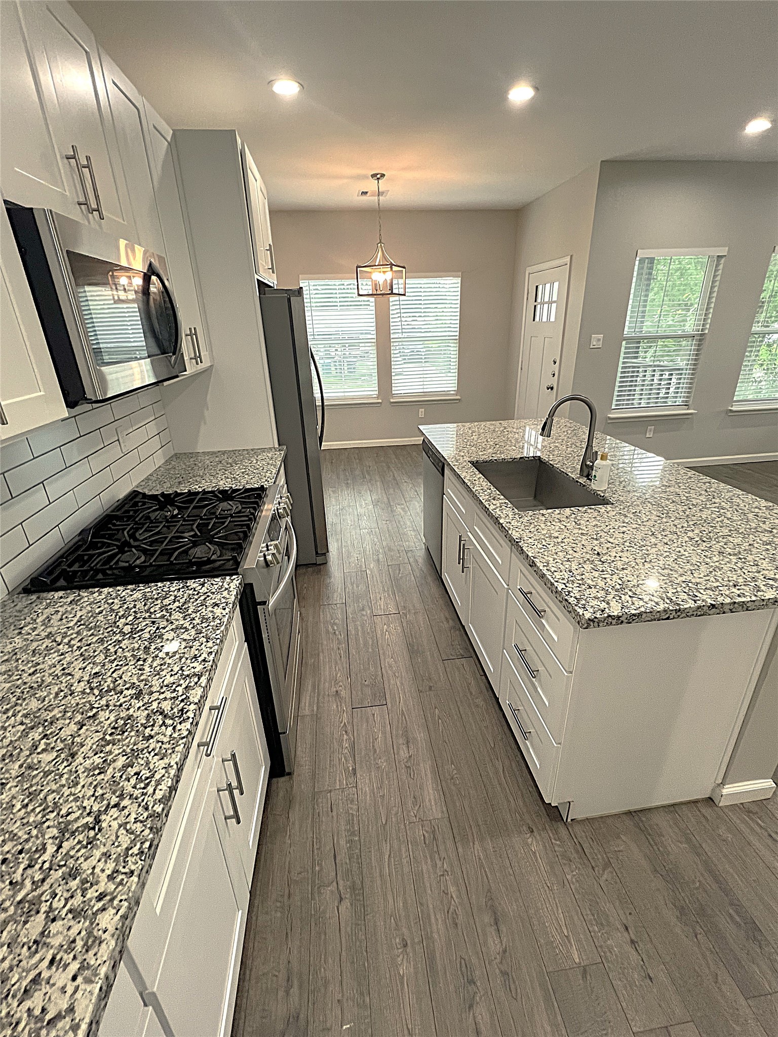 5779 Belarbor Street, Unit A Houston, TX 77033 - Photo 9 of 27 a kitchen with kitchen island granite countertop a stove a sink a refrigerator and blue cabinets with wooden floor