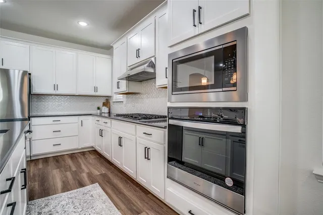 a kitchen with granite countertop white cabinets and stainless steel appliances