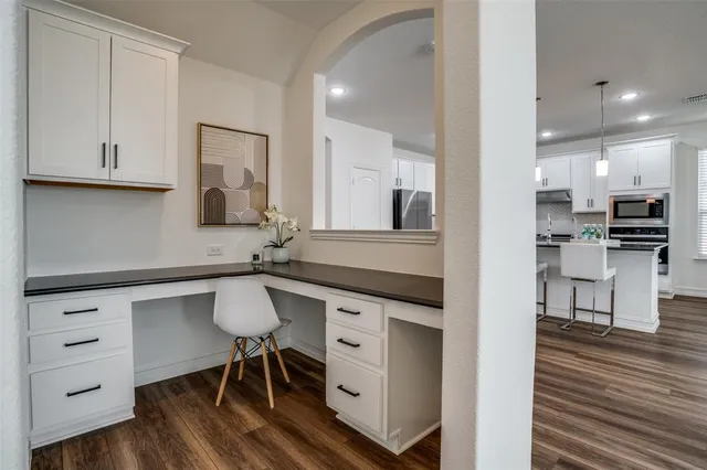 a kitchen with white cabinets and chairs