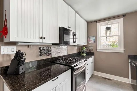 a kitchen with granite countertop a sink a stove and cabinets