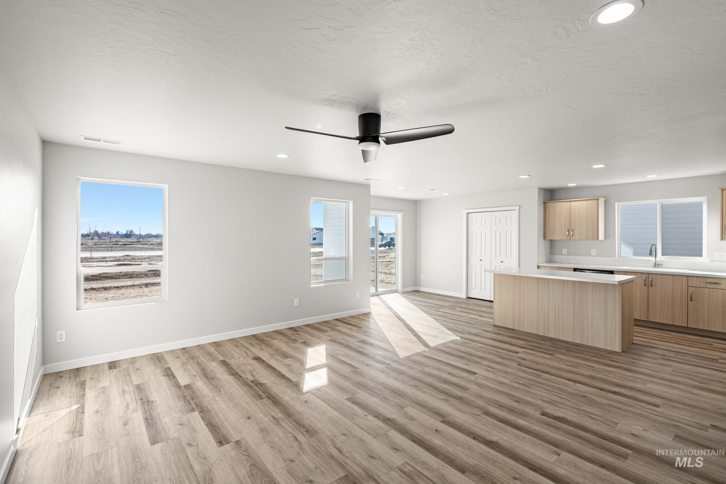 1647 Dyer Street Middleton, ID 83644 - Photo 9 of 25 Unfurnished living room with a ceiling fan, light wood-style flooring, recessed lighting, and a textured ceiling
