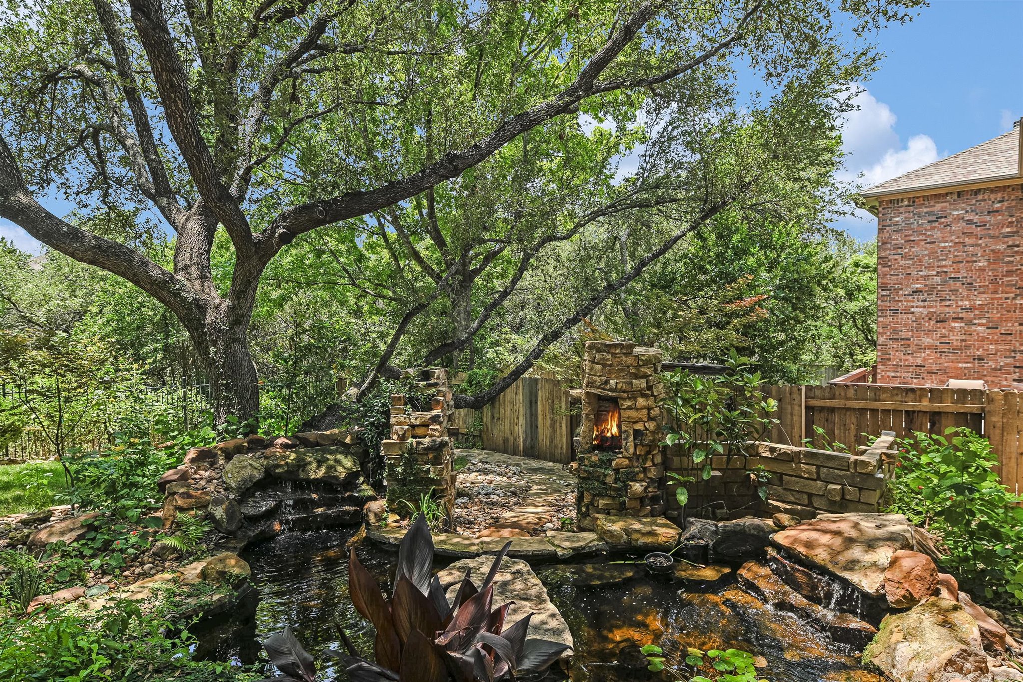 2849 Grimes Ranch Road Austin, TX 78732 - Photo 28 of 31 A tranquil garden oasis with a charming stone waterfall and an inviting outdoor fireplace.