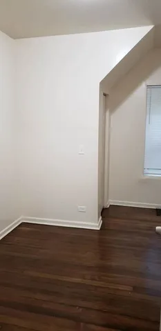 a view of an empty room with wooden floor and closet