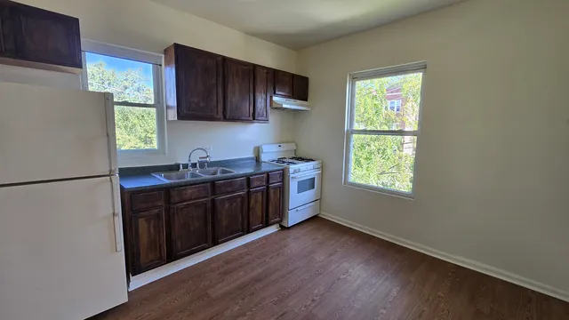 a kitchen with stainless steel appliances granite countertop a refrigerator a sink dishwasher a stove and a refrigerator with wooden floor