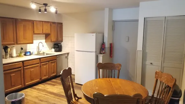 a kitchen with stainless steel appliances granite countertop a refrigerator a sink a stove a dining table and chairs