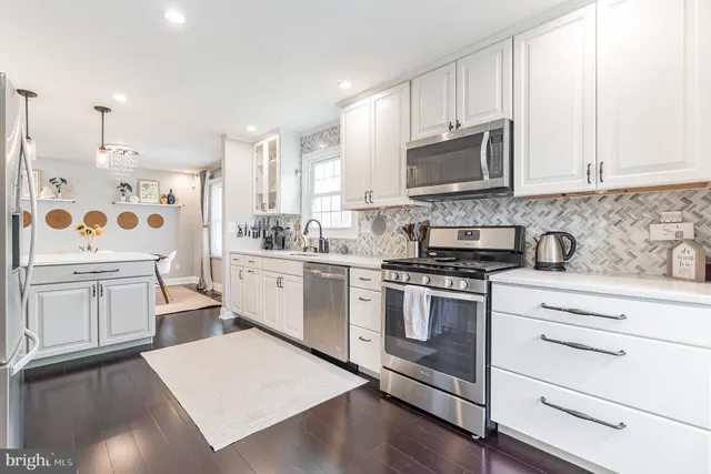 a kitchen with white cabinets sink and stainless steel appliances