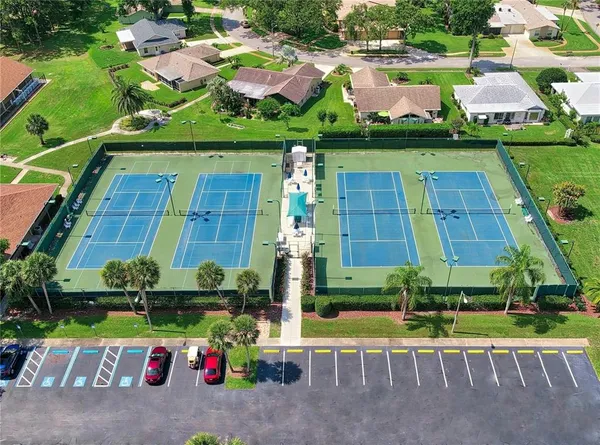 a view of a tennis ground with large trees