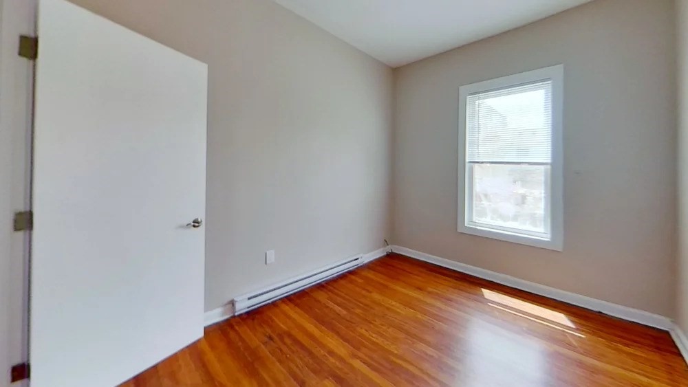 121 George Street, Unit 2 Boston, MA 02119 - Photo 7 of 8 a view of an empty room with wooden floor and a window