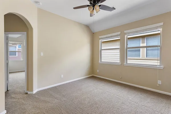 an empty room with windows and fan
