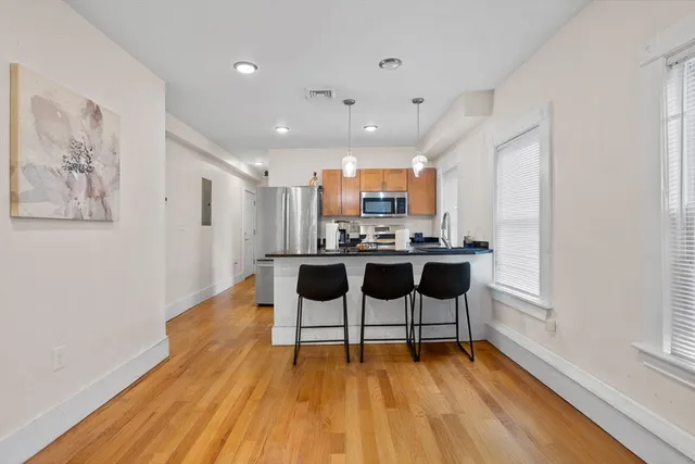 a living room with furniture and kitchen view with wooden floor