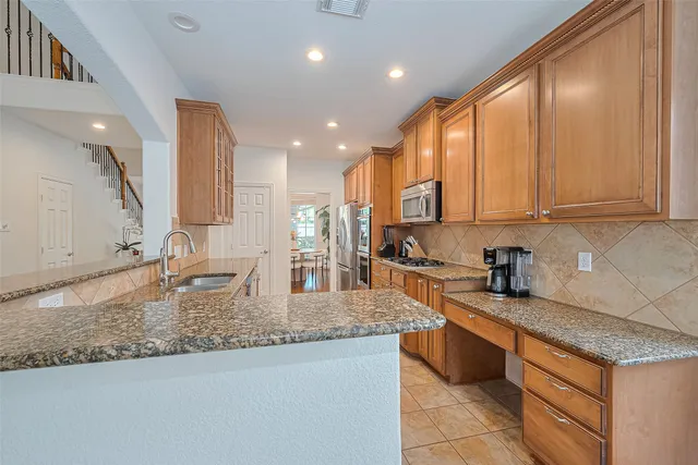 a kitchen with stainless steel appliances granite countertop a refrigerator a stove and a sink