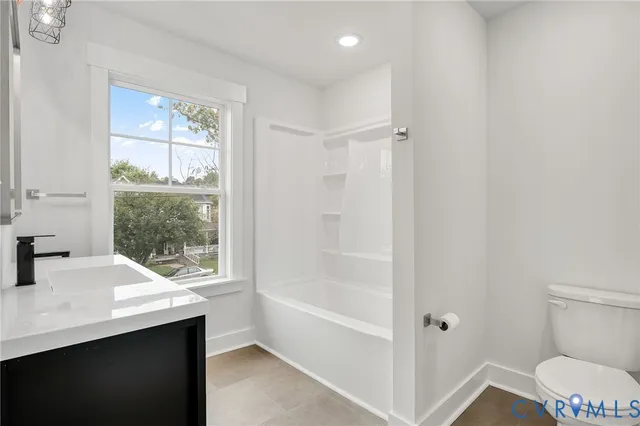 a bathroom with a toilet a sink a window and mirror