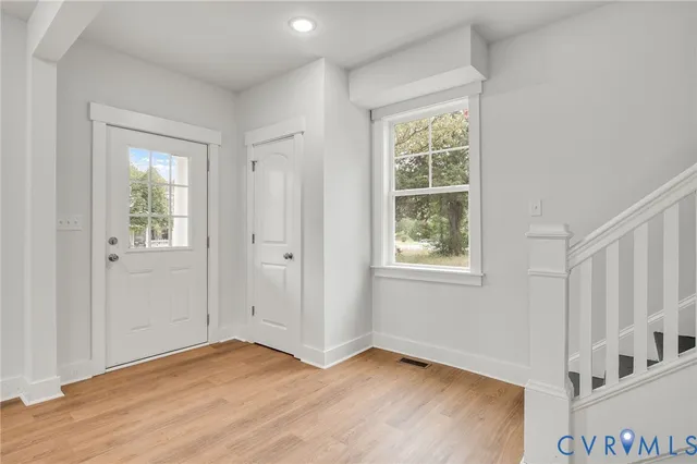 an empty room with wooden floor chandelier and windows