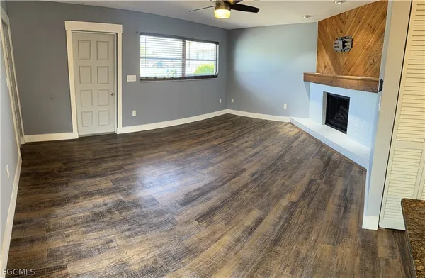 an empty room with wooden floor cabinet and windows
