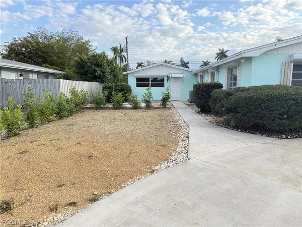 a view of a house with a yard plants and large tree