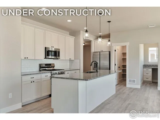 a kitchen with stainless steel appliances kitchen island granite countertop a stove a sink a refrigerator and white cabinets with wooden floor