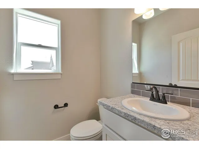 a bathroom with a granite countertop sink a mirror and a toilet
