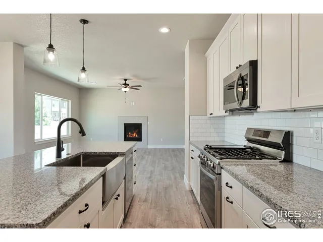 a kitchen with stainless steel appliances granite countertop a sink a stove and a wooden cabinets