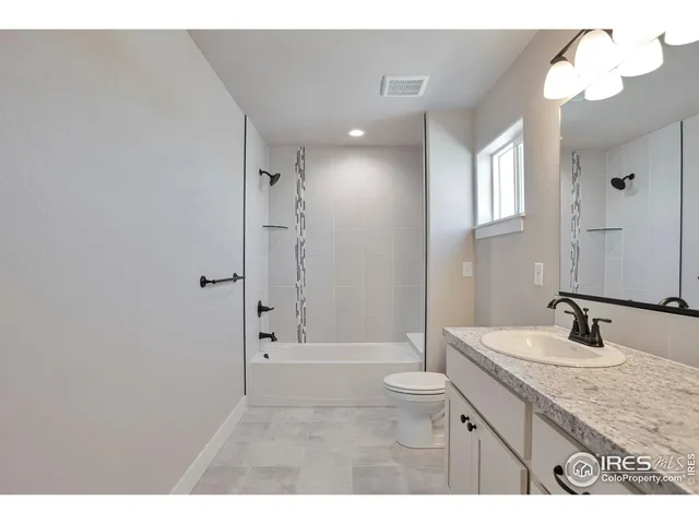 a bathroom with a granite countertop sink a toilet and shower