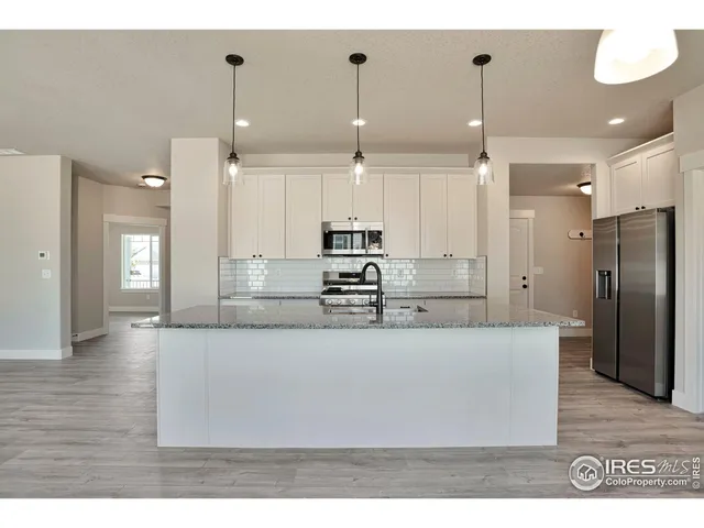 a large kitchen with stainless steel appliances kitchen island a refrigerator and a wooden floor