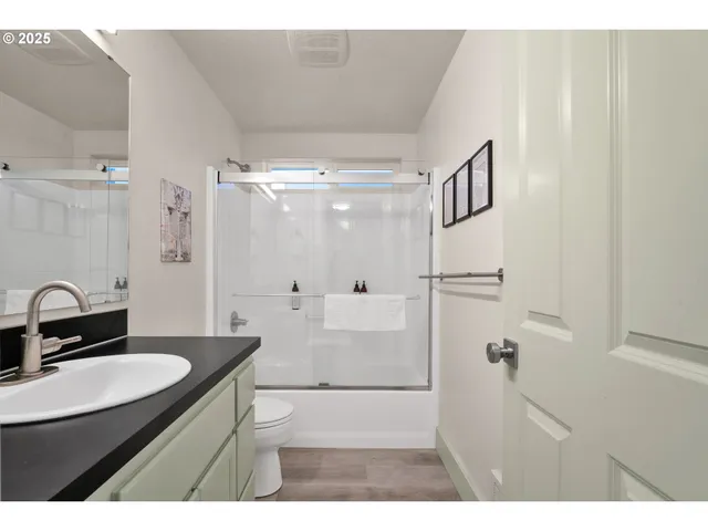 a bathroom with a sink a toilet a mirror and shower