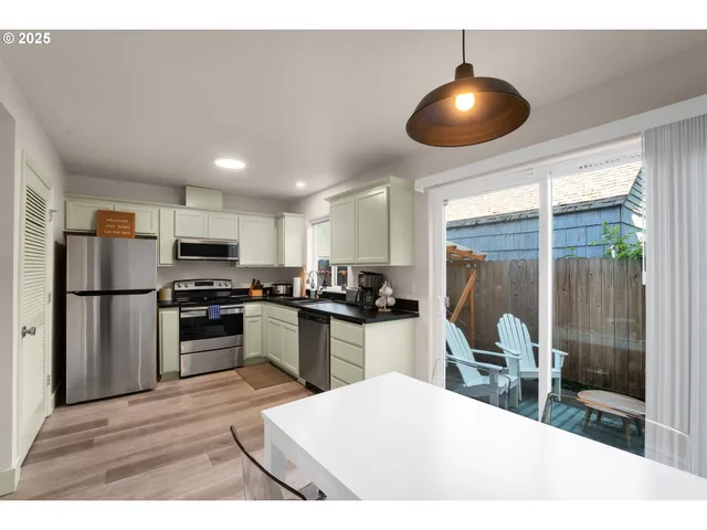 a kitchen with stainless steel appliances kitchen island granite countertop a refrigerator a stove a sink a dining table and chairs