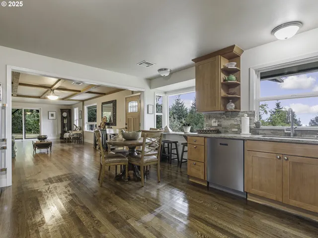 a dining hall with stainless steel appliances granite countertop a stove and a view of living room
