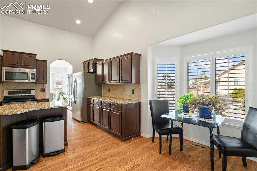 10658 Pictured Rocks Drive Peyton, CO 80831 - Photo 10 of 36 a kitchen with stainless steel appliances granite countertop a stove top oven a sink dishwasher a dining table and chairs with wooden floor