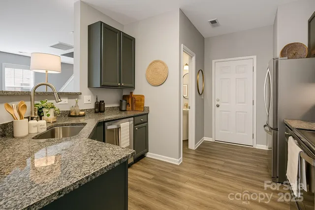 a kitchen with granite countertop a refrigerator a stove and a sink with wooden floor