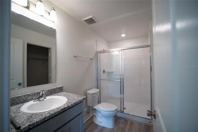 a bathroom with a granite countertop sink toilet and shower