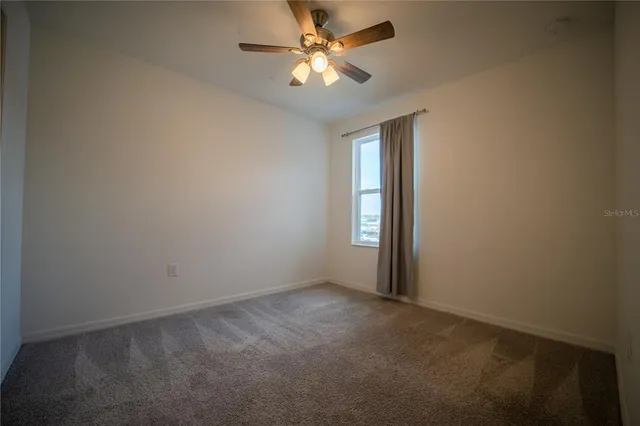 a view of an empty room and chandelier fan