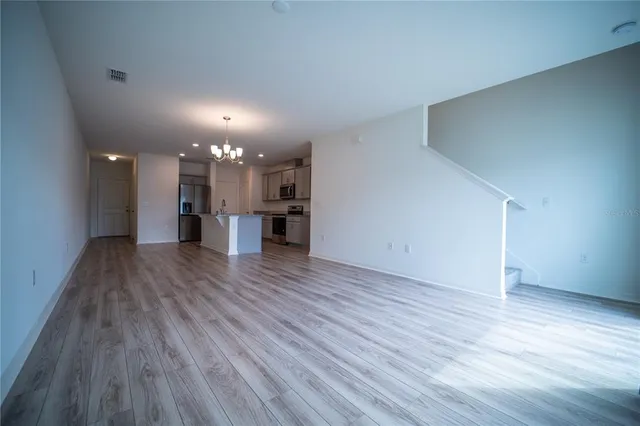 a view of a room with wooden floor and a kitchen