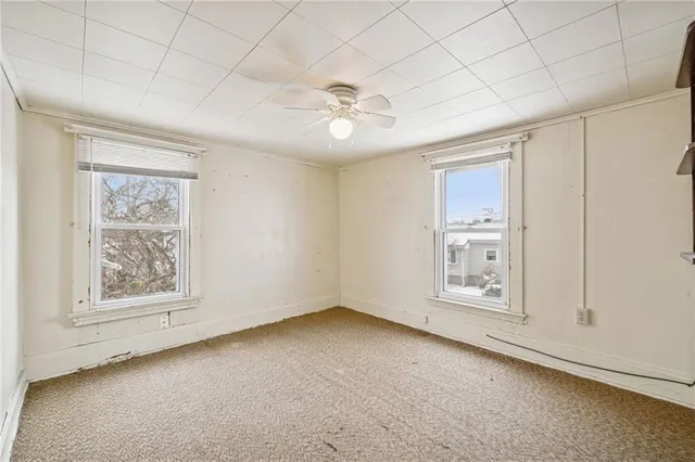 an empty room with windows and fan