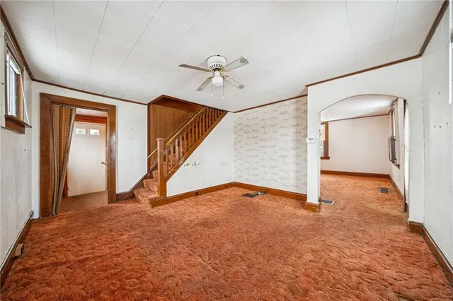 an empty room with staircase and a ceiling fan