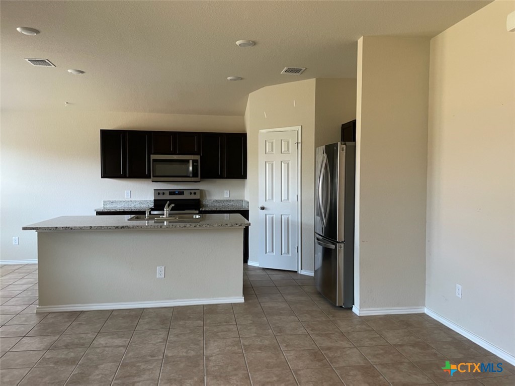 6114 Sally Ride Lane Killeen, TX 76543 - Photo 4 of 21 a living room with stainless steel appliances a refrigerator a stove a microwave and cabinets