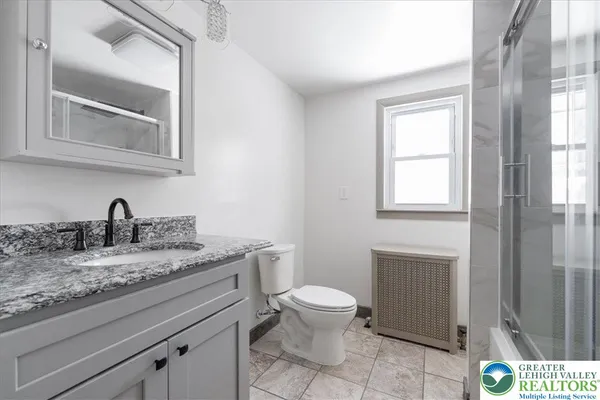 a bathroom with a granite countertop toilet sink and mirror
