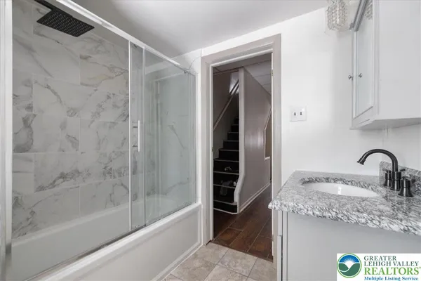 a bathroom with a granite countertop sink a mirror and shower